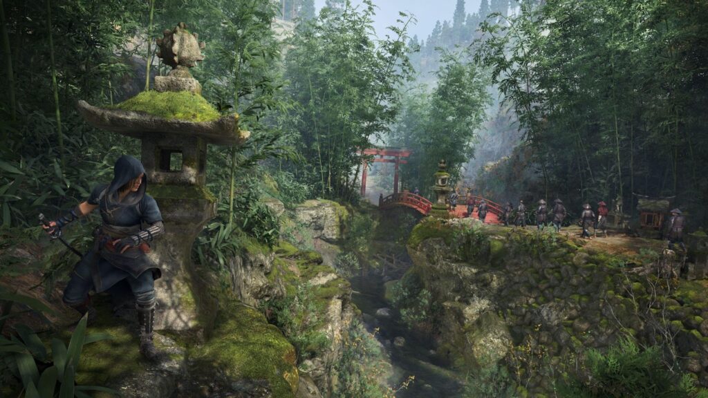 Personagem em primeiro plano:
Uma assassina vestida com roupas escuras e capuz, escondida atrás de uma grande lanterna de pedra tradicional japonesa (chamada tōrō).
Ela segura uma katana com uma das mãos e aparenta estar se preparando para agir furtivamente, observando os inimigos à distância.
Ambiente natural:
A vegetação é densa, com muito bambu, musgo e pedras, criando um ambiente úmido e sombrio.
Um riacho atravessa a parte inferior da cena, e há um grande desnível rochoso entre a assassina e o caminho onde os inimigos estão.
Ponte vermelha e torii:
Ao fundo, vemos uma clássica ponte arqueada vermelha, comum em templos japoneses, cruzando o riacho.
Um portão torii vermelho está logo após a ponte, simbolizando a entrada para uma área sagrada.
Inimigos ao fundo:
Um grupo de soldados patrulha o caminho, aparentemente alheio à presença da assassina.
Eles vestem armaduras tradicionais, com chapéus e lanças, indicando que essa parte do jogo exige aproximação furtiva.
Clima e atmosfera:
A cena transmite um forte senso de tensão e imersão, misturando o estilo clássico de stealth da franquia com a estética do Japão feudal. O uso de luz suave filtrada pelas árvores e a névoa leve reforçam a sensação de mistério e perigo iminente.